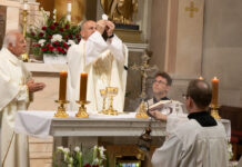 Štyri oltáriky, modlitby a procesia okolo chrámu. Veriaci v Bánovciach slávili Božie Telo Dekan Mgr. Gustáv Lutišan pozdvihuje Eucharistiu počas slávnostnej svätej omše. Vľavo hosťujúci kňaz Elemír Tassári.